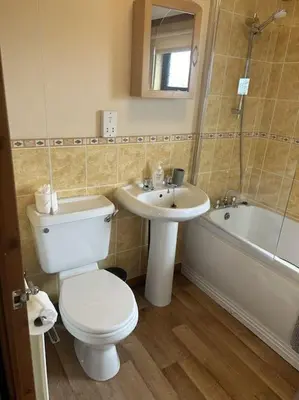 a bathroom with a toilet and a sink and a tub at Livingstones Lodge, Lake District in Plumbland