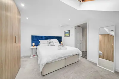 a white bedroom with a large bed and a mirror at Perfect location for beach and golfing in Troon