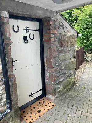a garage with two white garage doors in a brick wall at Annie's Cottage in Gosforth