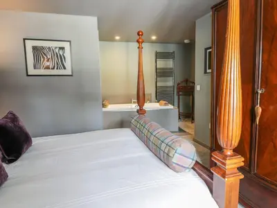 a bedroom with a bed with a wooden headboard at Wee Cottage in Moffat