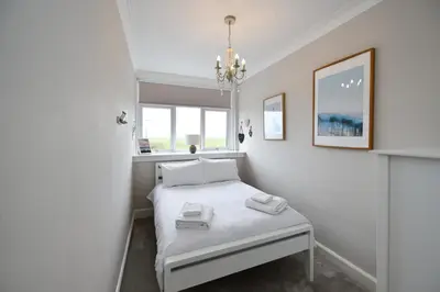 a small bedroom with a bed and a chandelier at Arran View in Prestwick in Prestwick