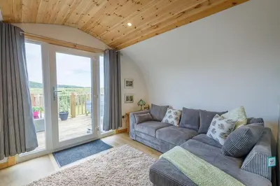 a living room with a couch and a large window at The Galloway Steading -The Hedgehog's Hideout family cabin with Hot Tub and Fire Pit in Glenluce