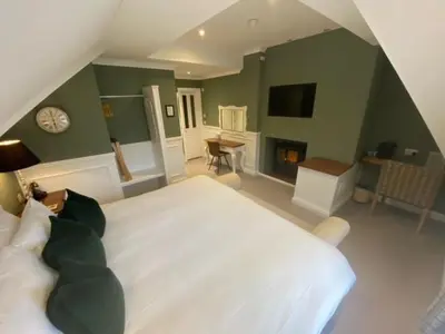 a bedroom with a large white bed and a fireplace at The Inn At Grasmere in Grasmere