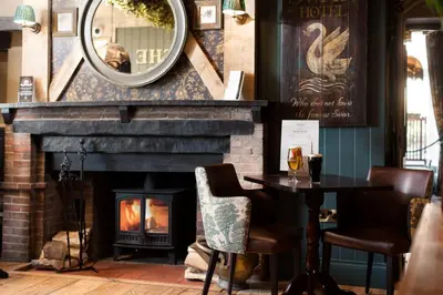 a fireplace in a restaurant with a table and a mirror at The Swan at Grasmere- The Inn Collection Group in Grasmere