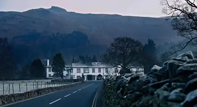 a house on the side of a road with a mountain at The Swan at Grasmere- The Inn Collection Group in Grasmere