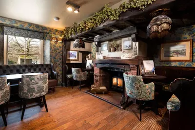 a living room with a fireplace and a table and chairs at The Swan at Grasmere- The Inn Collection Group in Grasmere