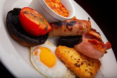 a plate of breakfast food with eggs bacon and beans at The Swan at Grasmere- The Inn Collection Group in Grasmere