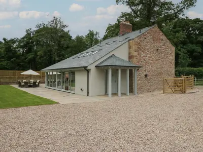 a brick building with a roof with a patio at Heather's Cottage in Carlisle