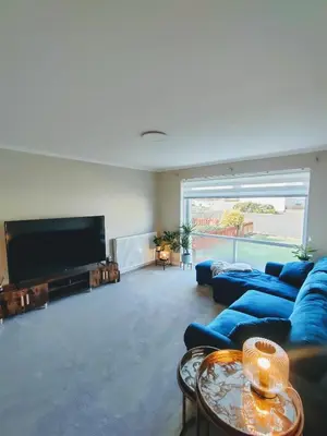 a living room with a blue couch and a flat screen tv at Troon Beach and Golf House in Barassie