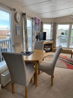 a living room with a table and chairs and a clock at 19 Forest Views in Plumbland