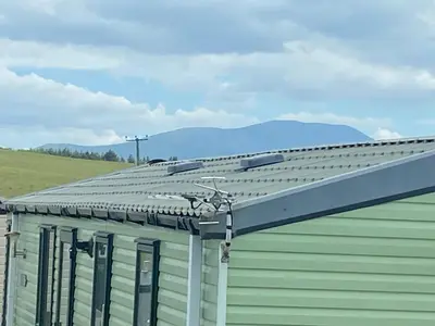 a roof of a building with mountains in the background at 19 Forest Views in Plumbland