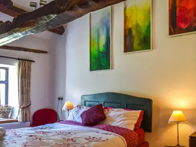 a bedroom with a bed and some paintings on the wall at Church House in Ulpha