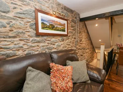 a leather couch in a room with a stone wall at Style Cottage in Keswick
