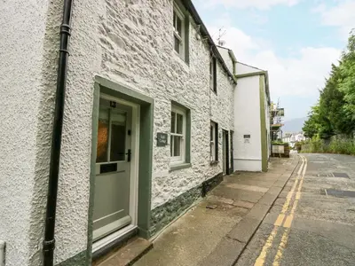 a white building with a green door on a street at Style Cottage in Keswick