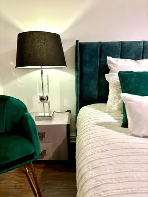 a bedroom with a bed with a green chair and a lamp at Golf View in Prestwick