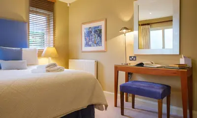 a bedroom with a bed and a desk with a mirror at Underscar - Manesty in Keswick