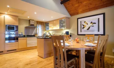a kitchen with a wooden table and a dining room at Underscar - Manesty in Keswick