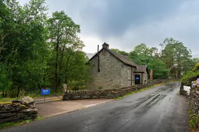 an old stone building on a road next to a road at Weirside, Chapel Stile in Ambleside