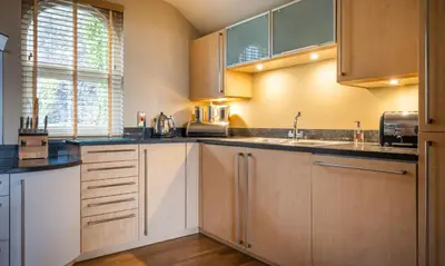 a kitchen with wooden cabinets and a sink at Underscar - Beckstones in Keswick