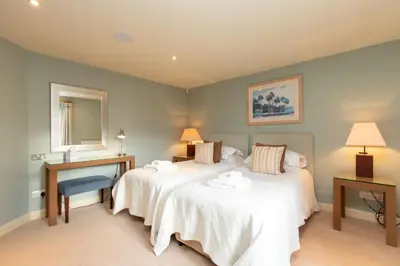 a bedroom with two beds and a desk and a mirror at Underscar - Skiddaw in Keswick