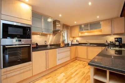 a kitchen with stainless steel appliances and wooden cabinets at Underscar - Skiddaw in Keswick