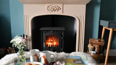 a fireplace in a living room with a table in front of it at Little Egret in Carsethorn