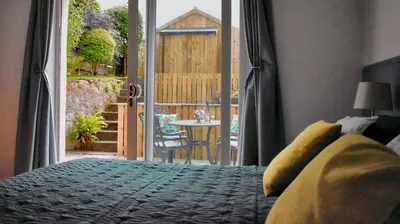 a bedroom with a bed and a door to a patio at Little Egret in Carsethorn