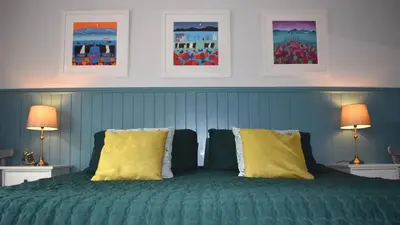 a bedroom with a green bed with two lamps at Little Egret in Carsethorn