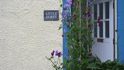a sign on the side of a building with purple flowers at Little Egret in Carsethorn