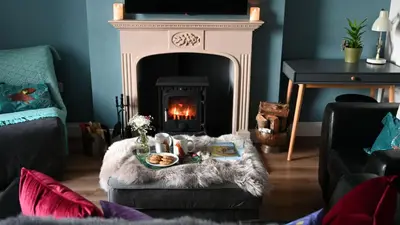 a living room with a fireplace and a table with food at Little Egret in Carsethorn