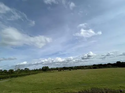 a large green field with a blue sky and clouds at wonderful 4 bedroom cottage sleeps 8 in Carlisle
