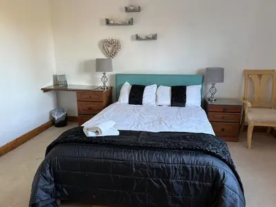 a bedroom with a large bed with a blue headboard at wonderful 4 bedroom cottage sleeps 8 in Carlisle