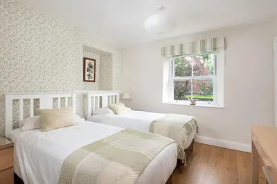 two beds in a white room with a window at Lydia's River Cottage in Keswick