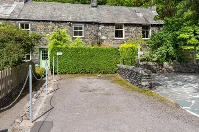 an old stone house with a fence in front of it at Lydia's River Cottage in Keswick
