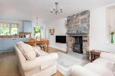 a living room with two white couches and a stone fireplace at Lydia's River Cottage in Keswick
