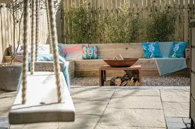 a patio with a bench and a bowl on a table at Kionslieu Farm Cottages in Foxdale