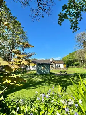a park with a bench and flowers in the grass at Kionslieu Farm Cottages in Foxdale