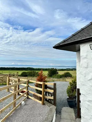 a wooden fence with a view of a field at Firth View 1 - Luxury Cottage with Sea View & Hot Tub, Ayr in Ayr