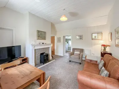 a living room with a couch and a fireplace at Rose Cottage in Port Logan