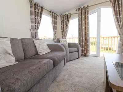 a living room with a couch and two windows at 31 Forest Views in Cockermouth