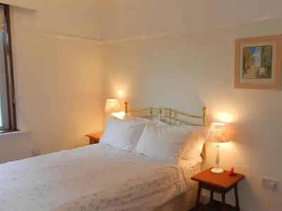 a bedroom with a white bed with two lamps at Ardbeag in Whiting Bay