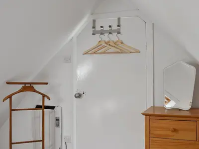 a room with a white door with wooden hangers at Ivy Cottage in Whiting Bay