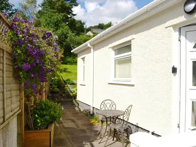 a patio with a table and chairs and flowers at Oakvale - Oak Leaf in Braithwaite