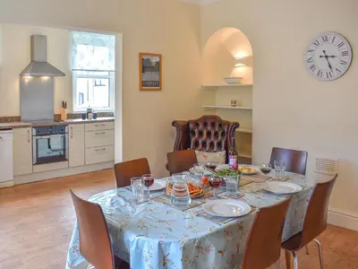 a dining room with a table and chairs and a clock at Cumberland Place in Keswick