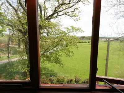 an open window with a view of a green field at Rowan Cottage in Borgue