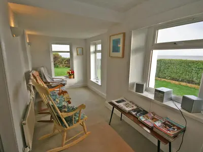 a living room with a chair and a table and a window at East Cottage in Mainsriddle