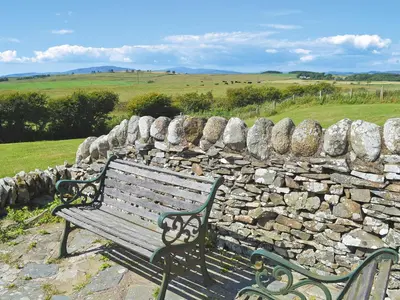 a bench sitting in front of a stone wall at Allanhead in Borgue