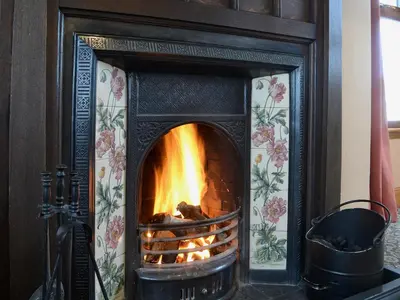 a fireplace with a fire in it at Allanhead in Borgue