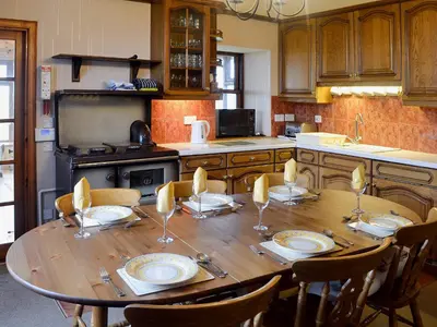 a kitchen with a wooden table with plates and chairs at Allanhead in Borgue