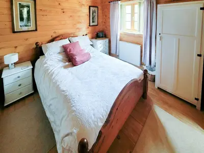 a bedroom with a bed with a pink pillow on it at Forest Lodge in Dumfries
